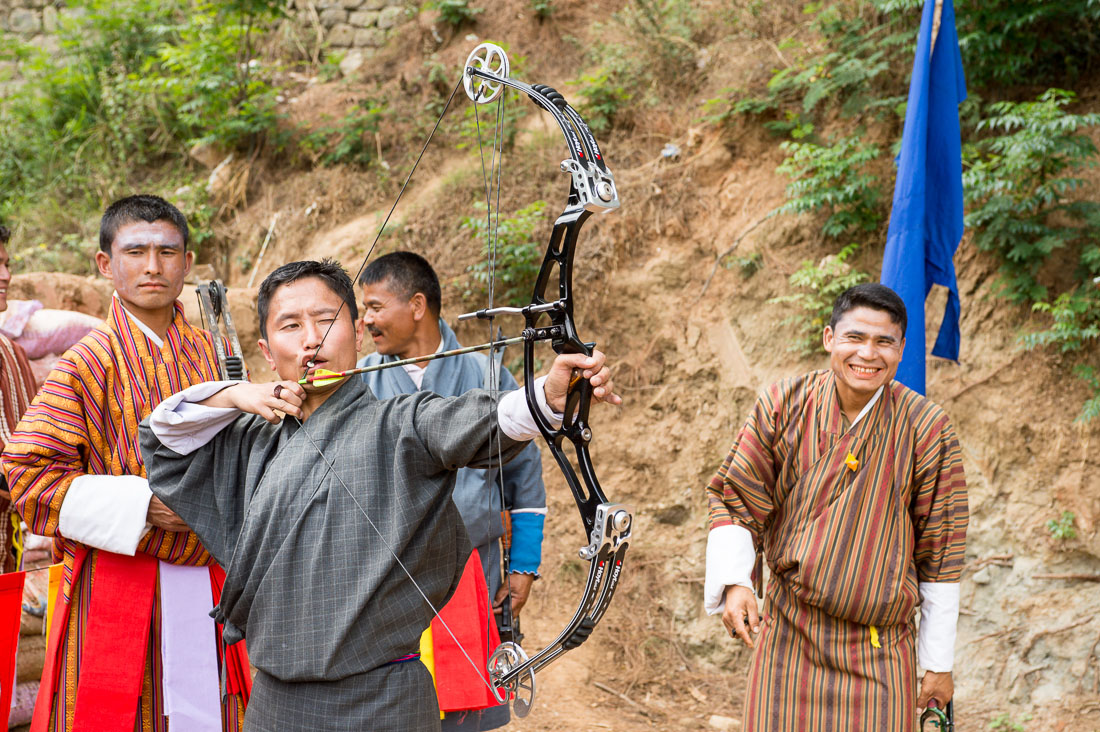 Archer, wearing traditional Bhutanese costume, shooting at 500 feet target using a modern compuond bow Kingdom of Bhutan, Asia