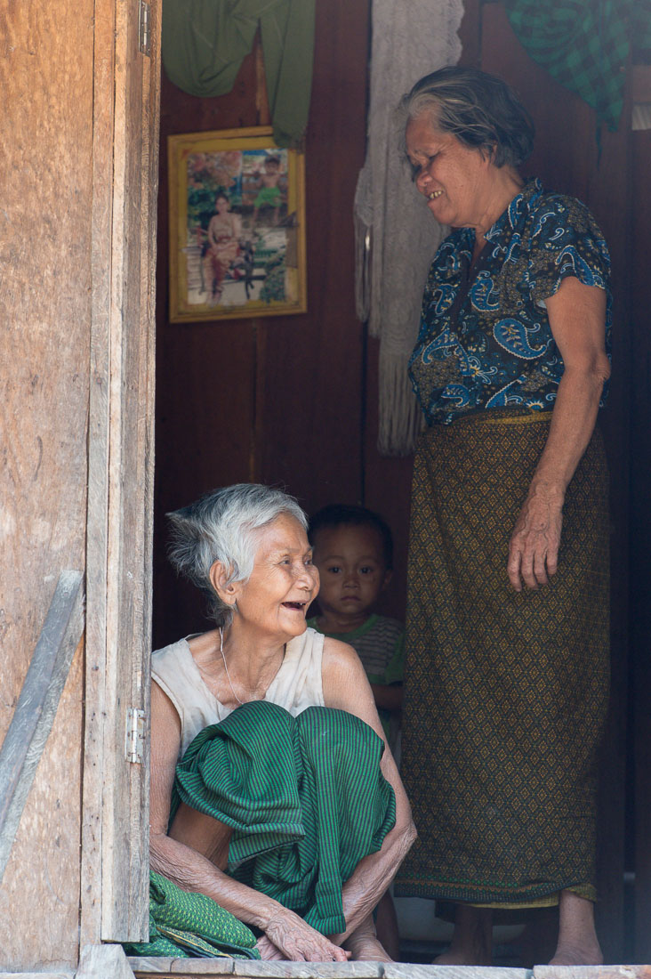 Old woman with her family, sitting in front of the front door, having good time. Virachey National Park, Ratanakiri province, Kingdom of Cambodia, Indochina, South East Asia