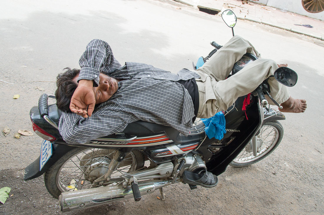 Taking a nap on the scooter; downtown Phnom Penh, Kingdom of Cambodia, Indochina, South East Asia.