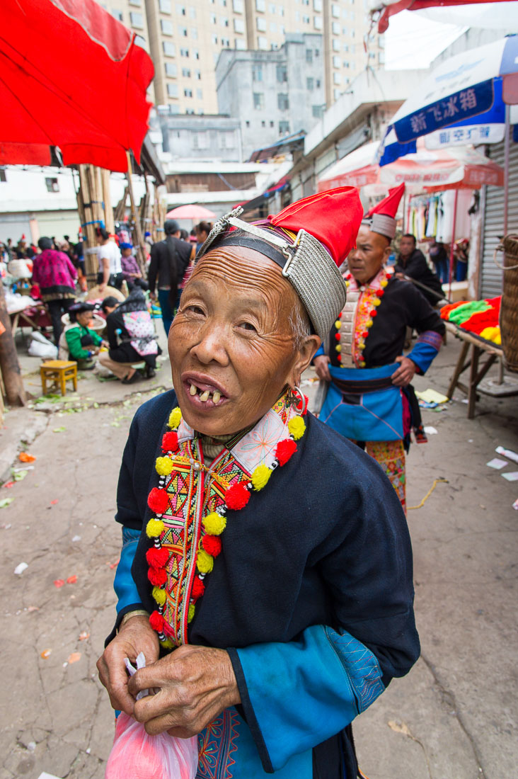 A joyful woman from the Yao ethnic minority people, in traditional costume, smiling at the photographer. Jin Ping market, Yunnan Province, China, Asia. Nikon D4, 24-120mm, f/4.0, VR