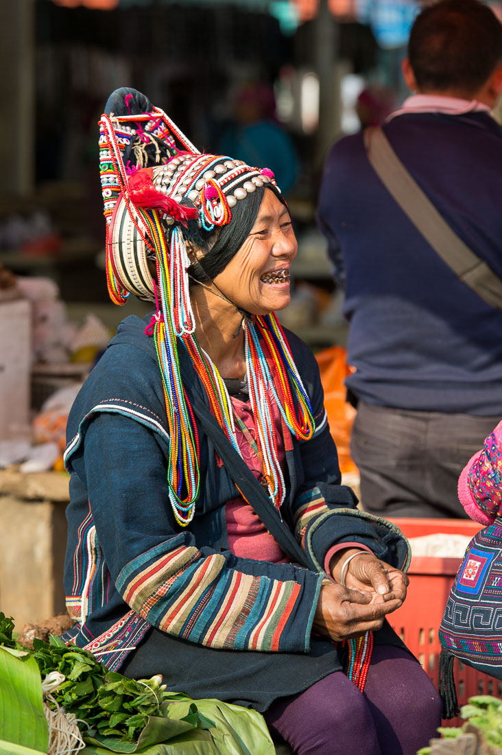 Joyful woman from the Ha Ni ethnic minority people in colorful costume, at Mang Xin market, Meng Lian County, Yunnan Province, China, Asia. Nikon D4, 70-200mm, f/2.8, VR II