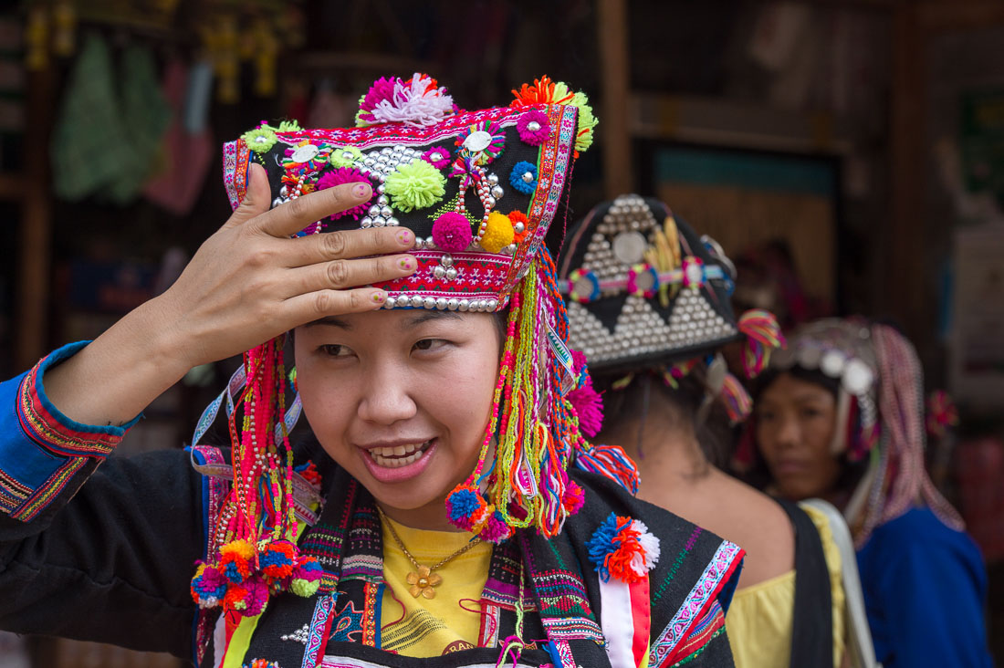 A woman from the Akha people ethnic minority wearing her traditional costume and an elaborate hat, at a village's market in Phongsali province. Lao PDR, Indochina, South East Asia