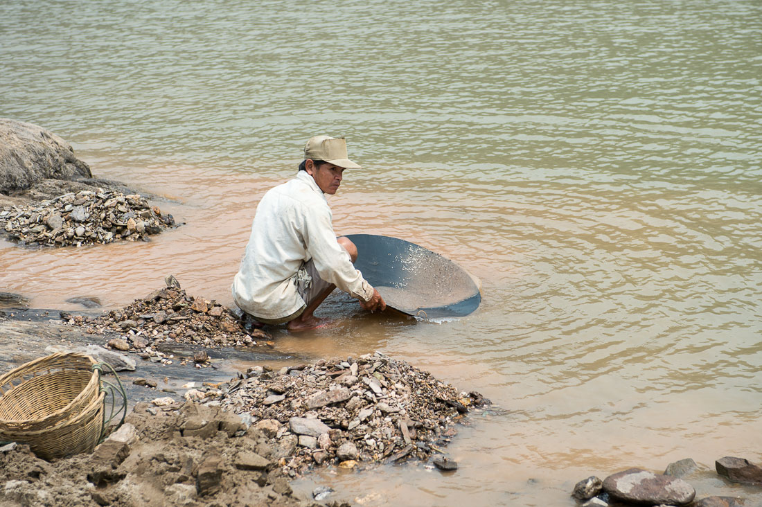 Unsophisticated gold mining on the Mekong river, washing the mud on the tray, hopfully looking for gold. Lao PDR, Laos, Indochina, South East Asia.