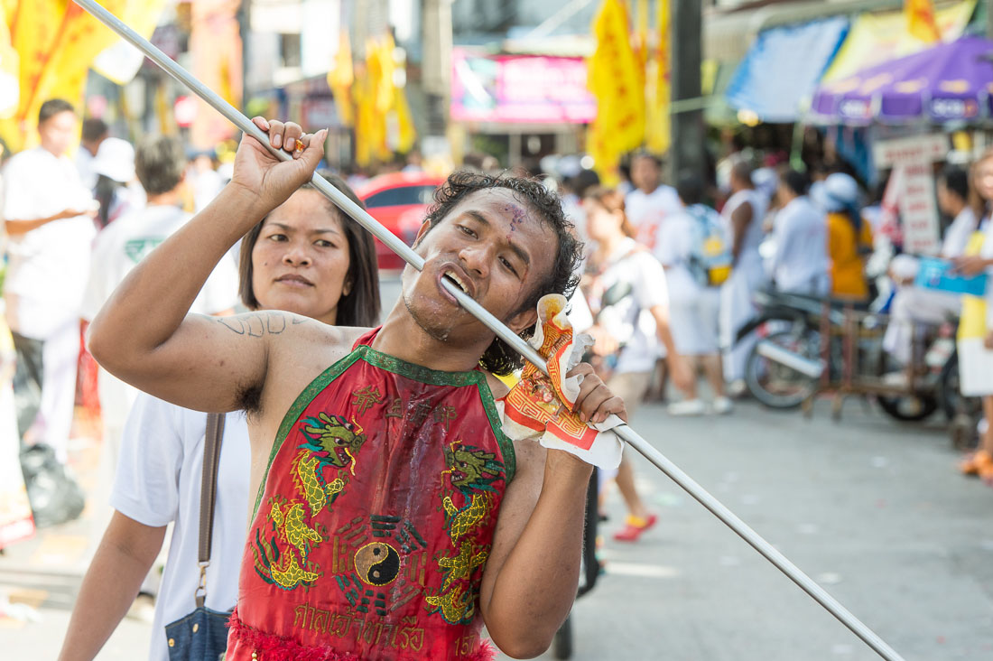 Psychic medium follower of the Bang New Shrine, with a long and thick rod pierced through his cheeck, taking part in a street procession during the annual Chinese vegetarian festival. Phuket, Kingdom of Thailand, Indochina, South East Asia