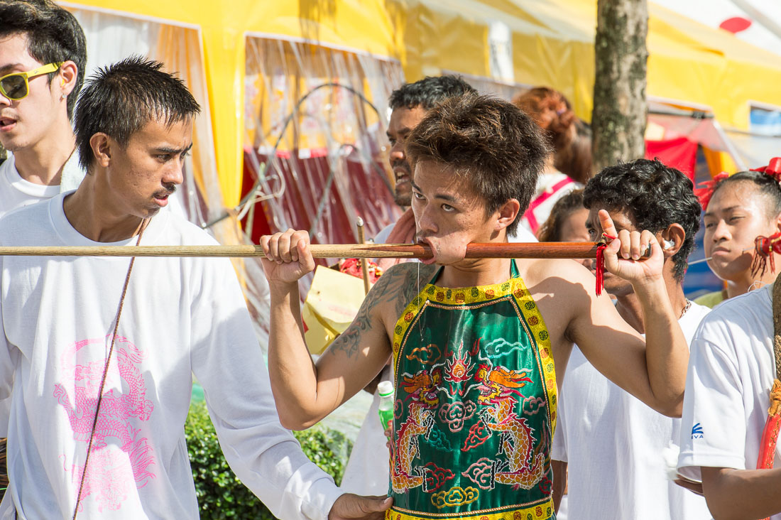 Psychic medium follower of the Bang New Shrine, with a billiard cue pierced through his cheeck, taking part in a street procession during the annual Chinese vegetarian festival. Phuket, Kingdom of Thailand, Indochina, South East Asia