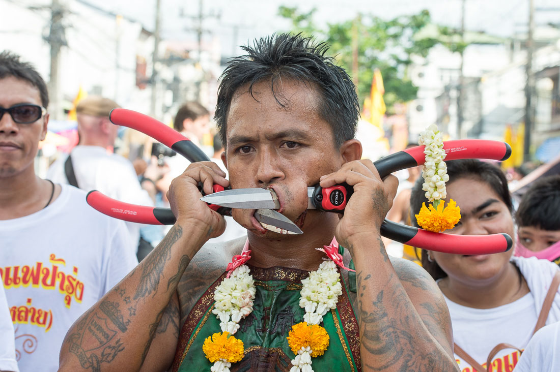 Psychic medium follower of the Bang New Shrine, with two large shears pierced through his cheecks, taking part in a street procession during the annual Chinese vegetarian festival. Phuket, Kingdom of Thailand, Indochina, South East Asia