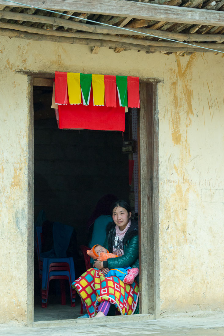 A mother from the Black Hmong people ethnic minority, sitting with her child at the door of her home, Ha Giang province. Viet Nam, Indochina, South East Asia.