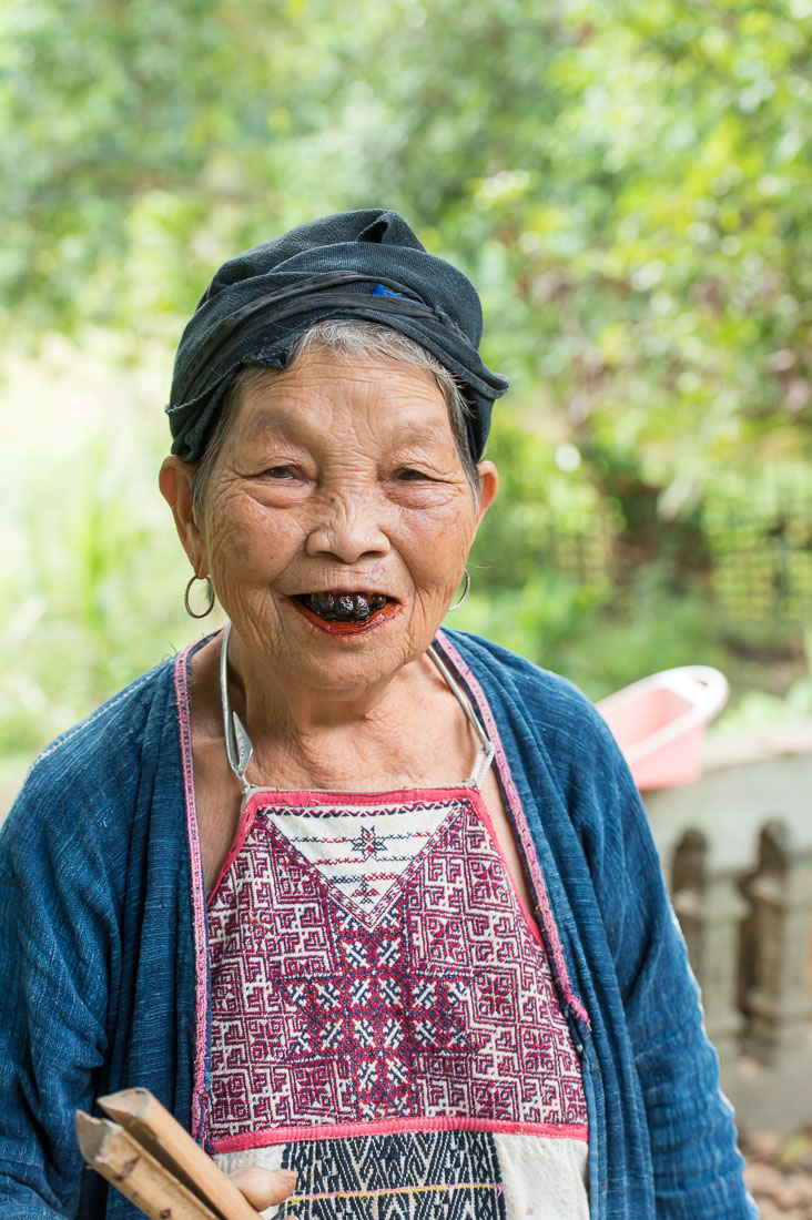 Very old woman from the Dao people ethnic minority group, showing her blackened teeth and the stained red lips from chewing areca nuts. Ngon Tue Village, Yen Bai Province, Viet Nam, Indochina, South East Asia.