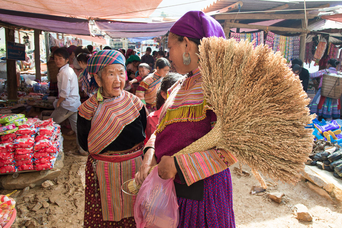 Two women from the Flower Hmong people ethnic minority group, wearing traditional clothes, chatting at the Can Cau market, Lao Cai province, Viet Nam, Indonesia, South East Asia