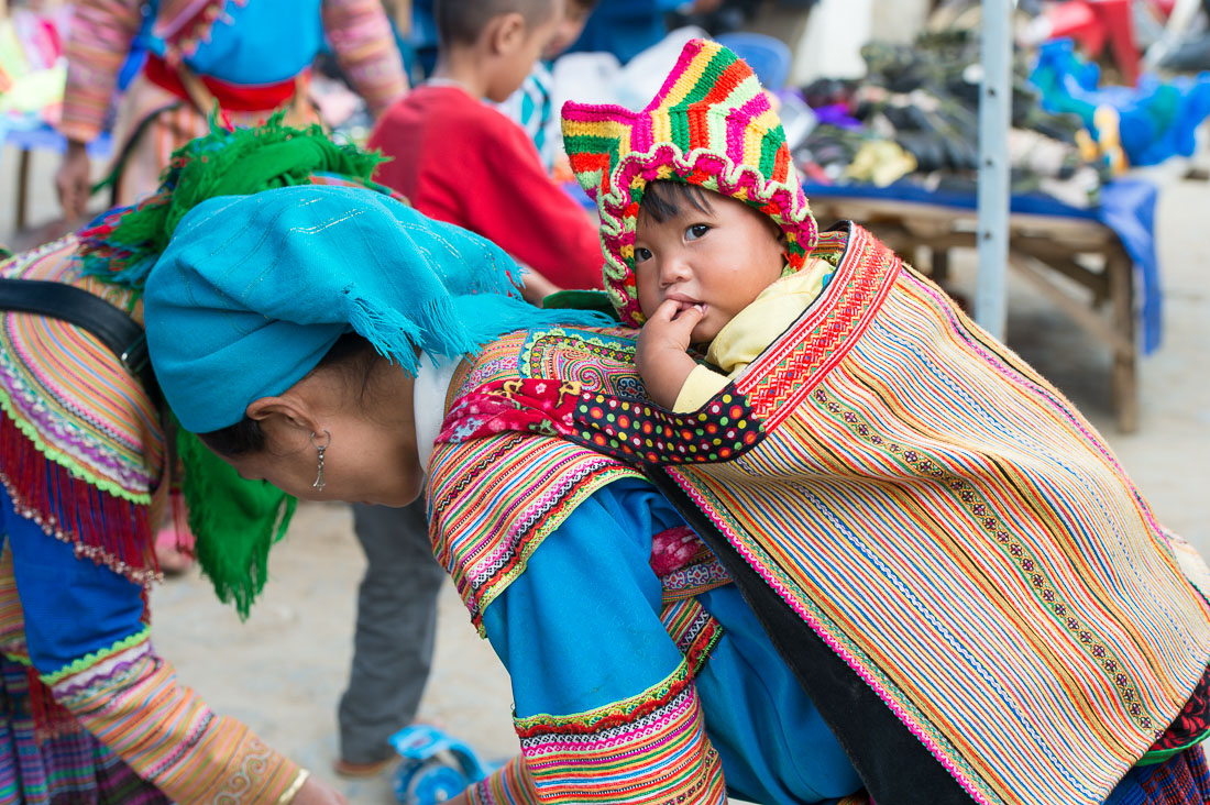 Young mother from the Flower Hmong people ethnic minority carrying her baby on a traditional back pak, Bac Ha market, Lao Cai Province, Viet Nam, Indochina, South East Asia