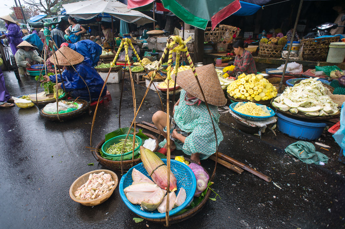 Vendor with her goods in baskets carried on bamboo shoulder pole, Huáº¿, Thua Thien-Hue province. Viet Nam, Indochina, South east Asia.