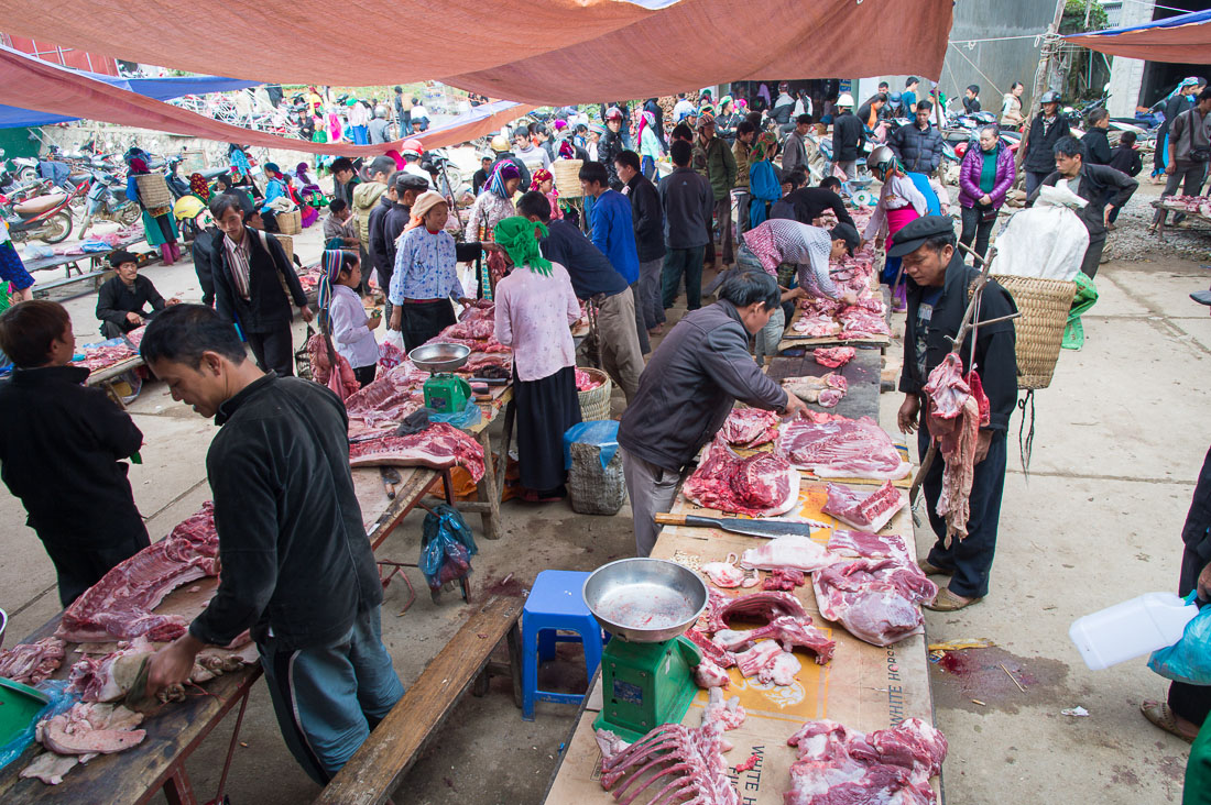 Butchers from the Black Hmong people ethnic minority group selling pig meat at the busy market in Dong Van, Ha Giang Province, Viet Nam, Indochina, South East Asia.