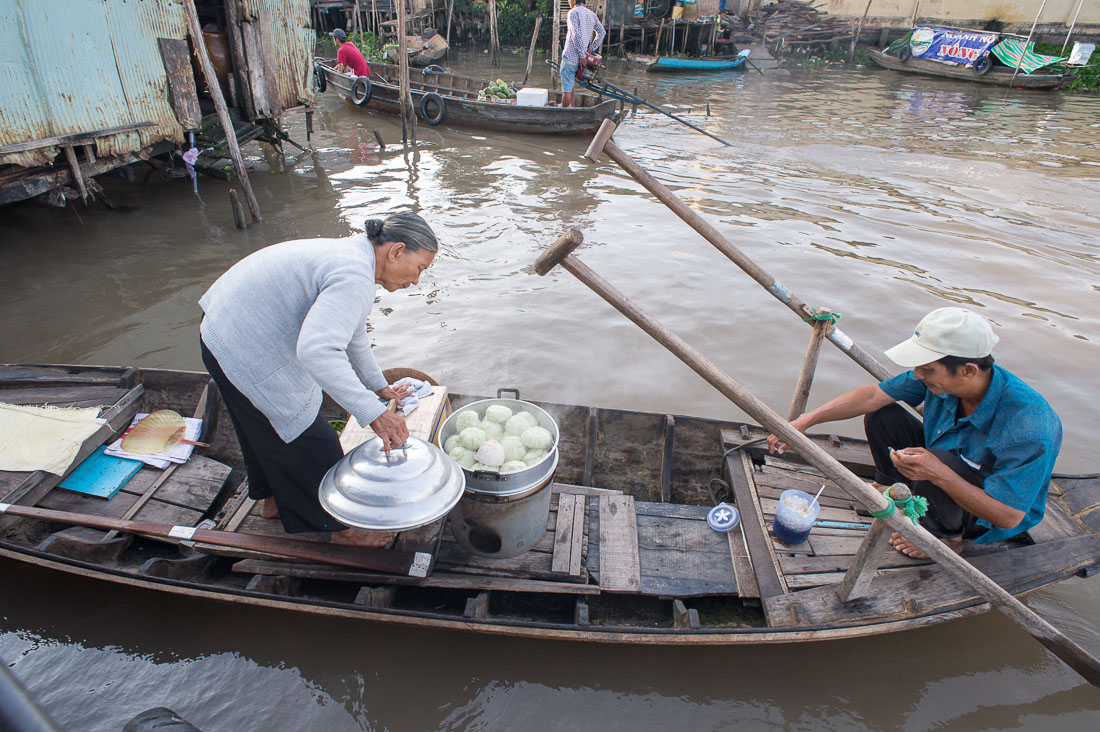 An old woman selling banh bao early morning at the Cai Rang vegetable floating market in the Mekong River Delta, Can Tho, Hau Giang Province, Viet Nam, Indochina, South East Asia.