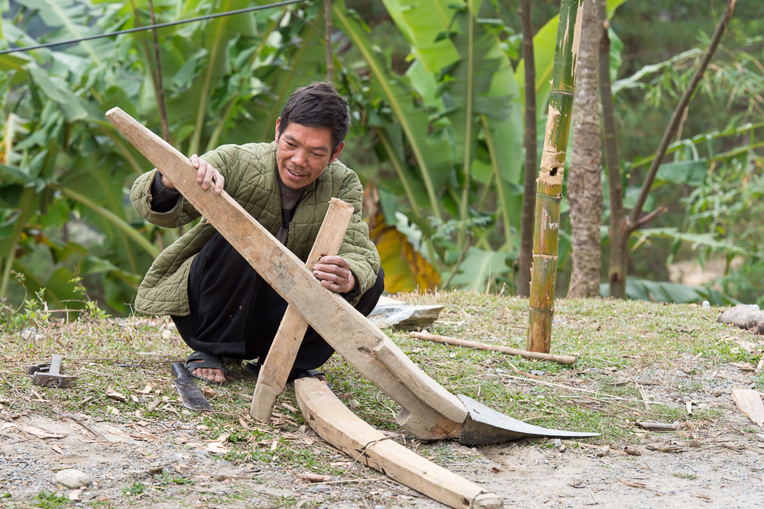 A man, from the Black Hmong ethnic minority, trying to put together a plow for the incoming rice season. Viet Nam, Indochina, South East Asia.