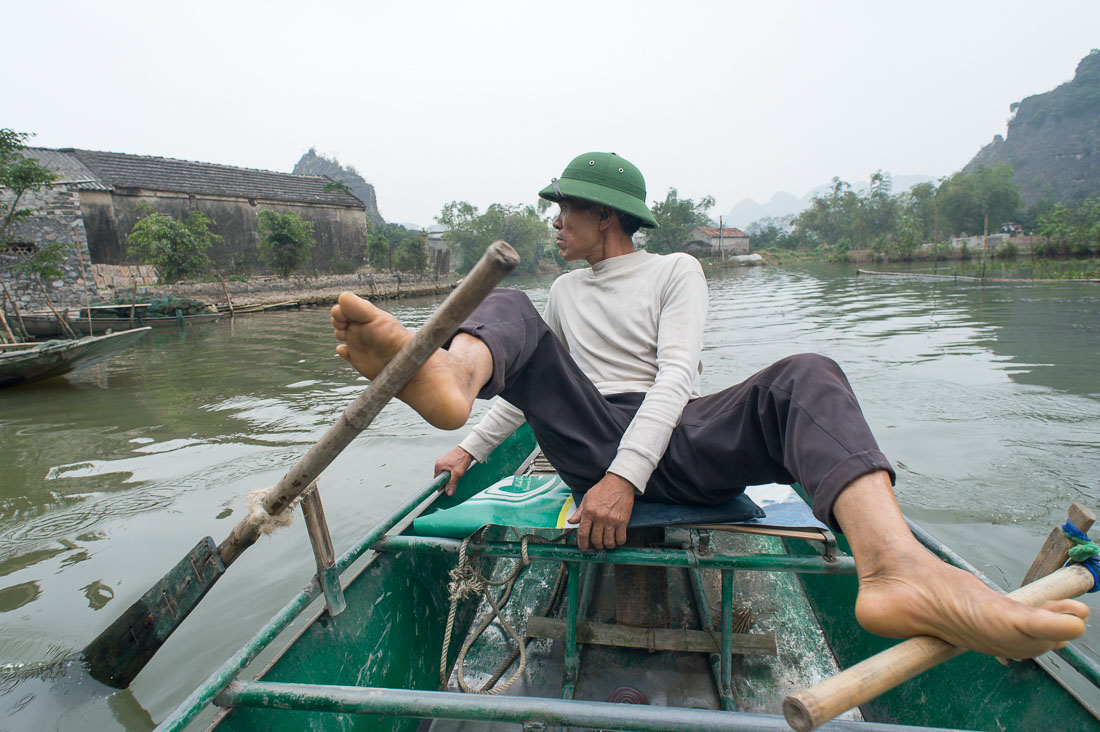 Unusual practice of rowing with feet on the Ngo Dong river, Tam Coc - Bich Dong, Ninh Binh Province. Ninh Binh Province. Viet Nam, Indochina, South East Asia.