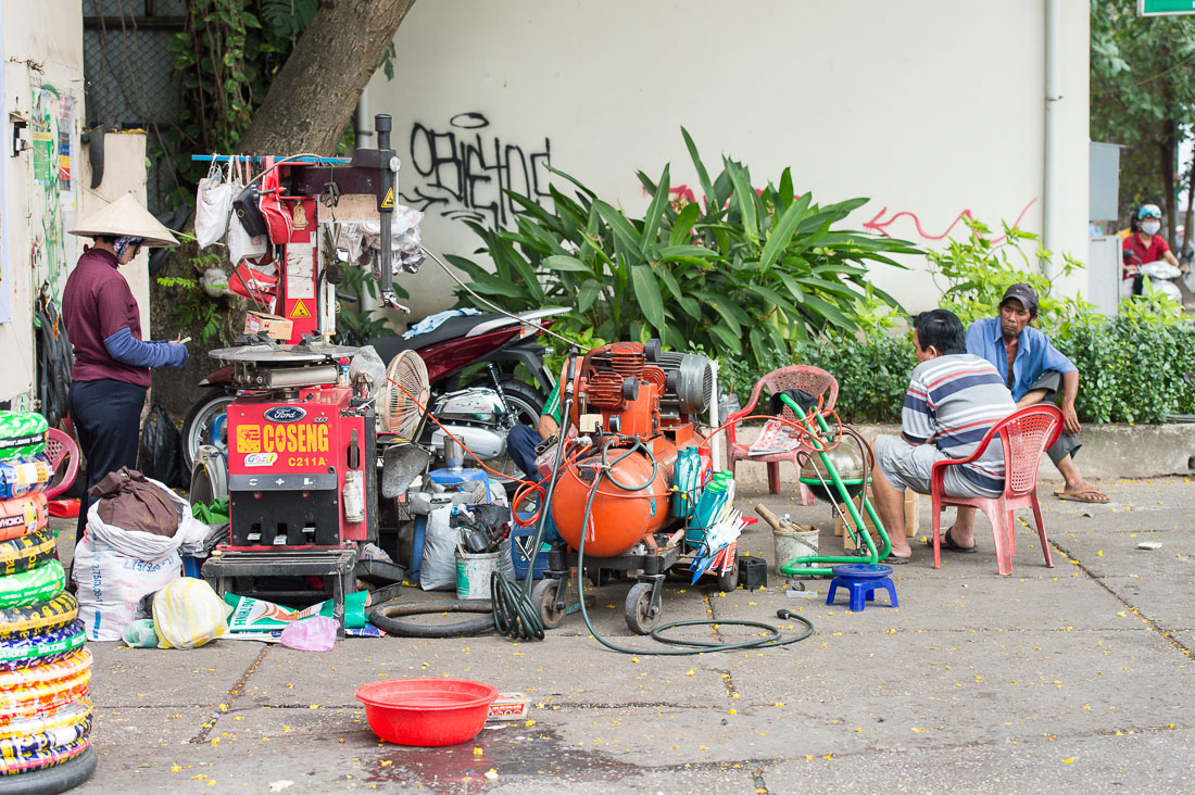 A tire repair shop operating on the walkside, fully equipped with industrial air compressor and hand free tire changer, Ho Chi Minh City (Saigon). Viet Nam, Indochina, South East Asia.