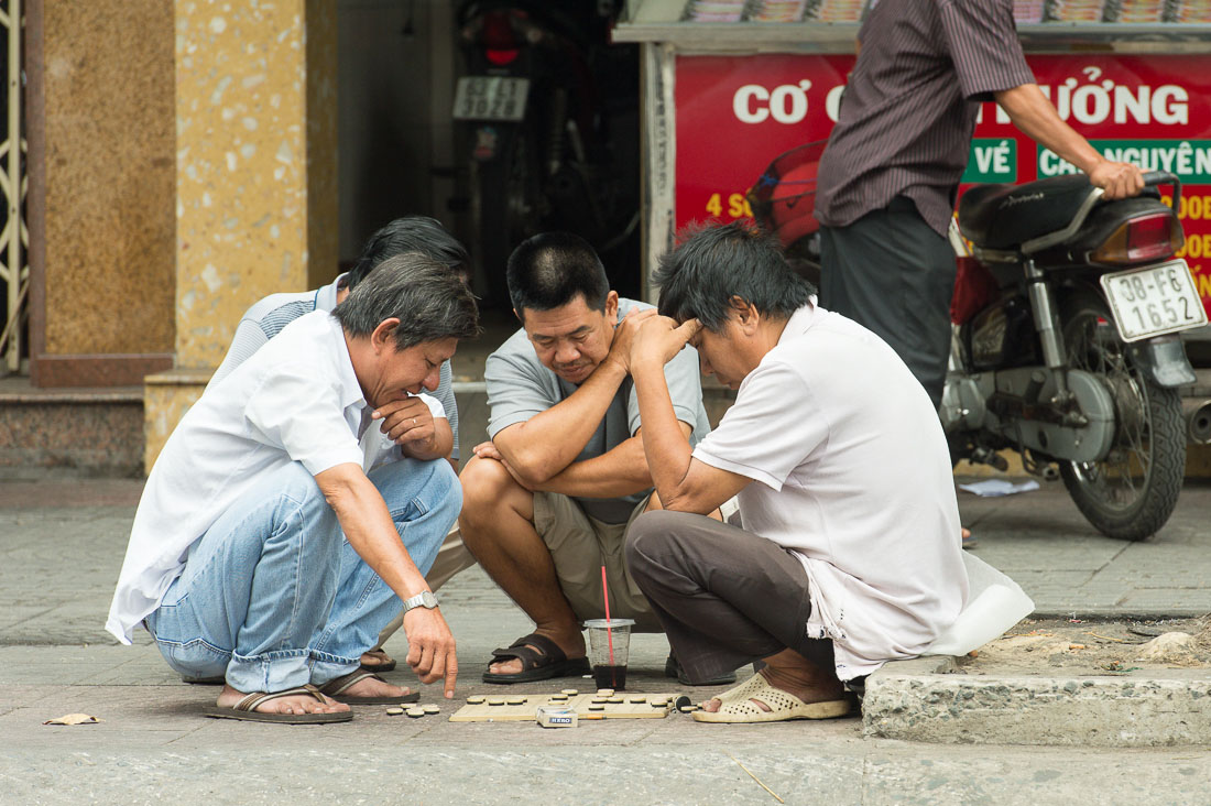 Hard work,  men playing Chinese chess on the street of Ho Chi Minh City (Saigon). Viet Nam, Indochina, South East Asia.