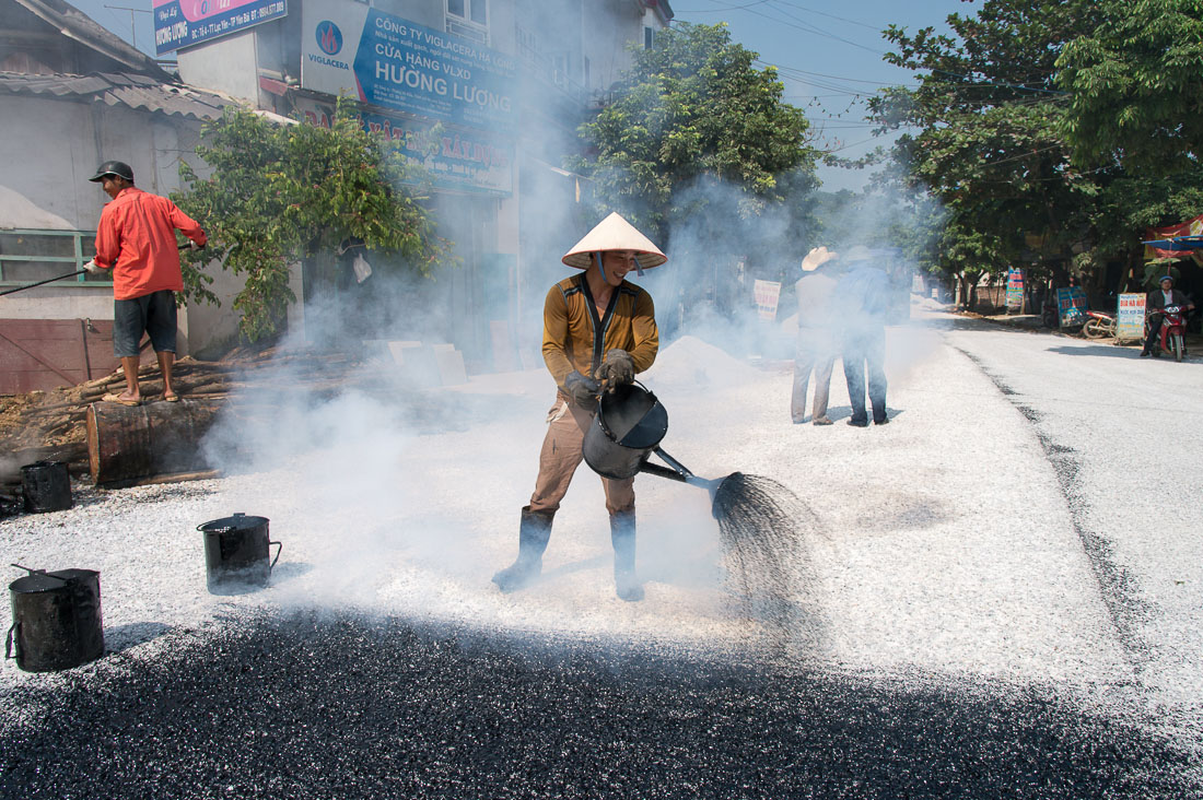 Vietnamese worker puoring hot tar on road under construction, Yen The, Yen Bai Province, Viet Nam, Indochina, South East Asia.