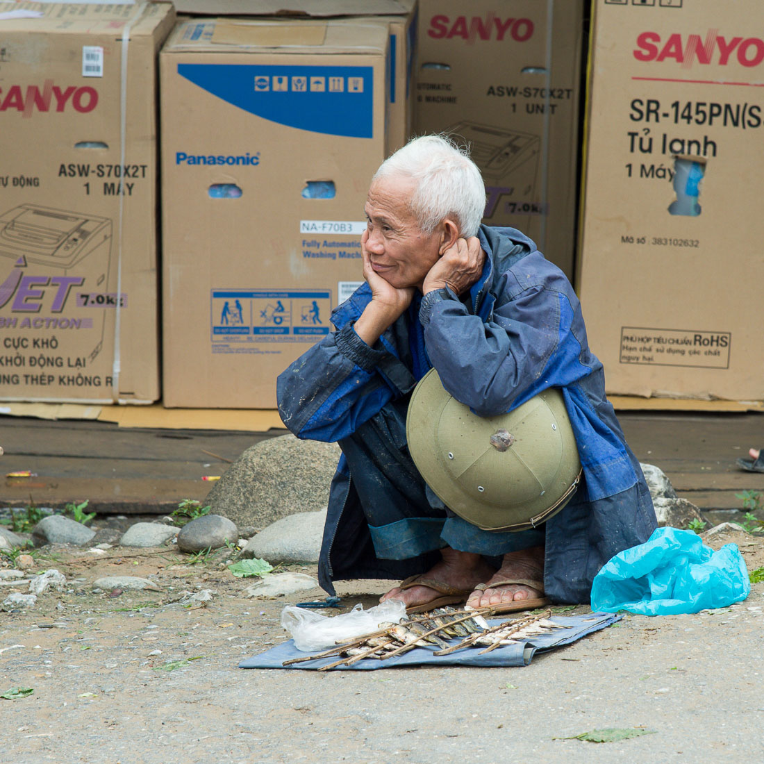 Old man selling few small river fishes at the Bao Lac market. Cao Bang Province, Viet Nam, Indochina, South East Asia.